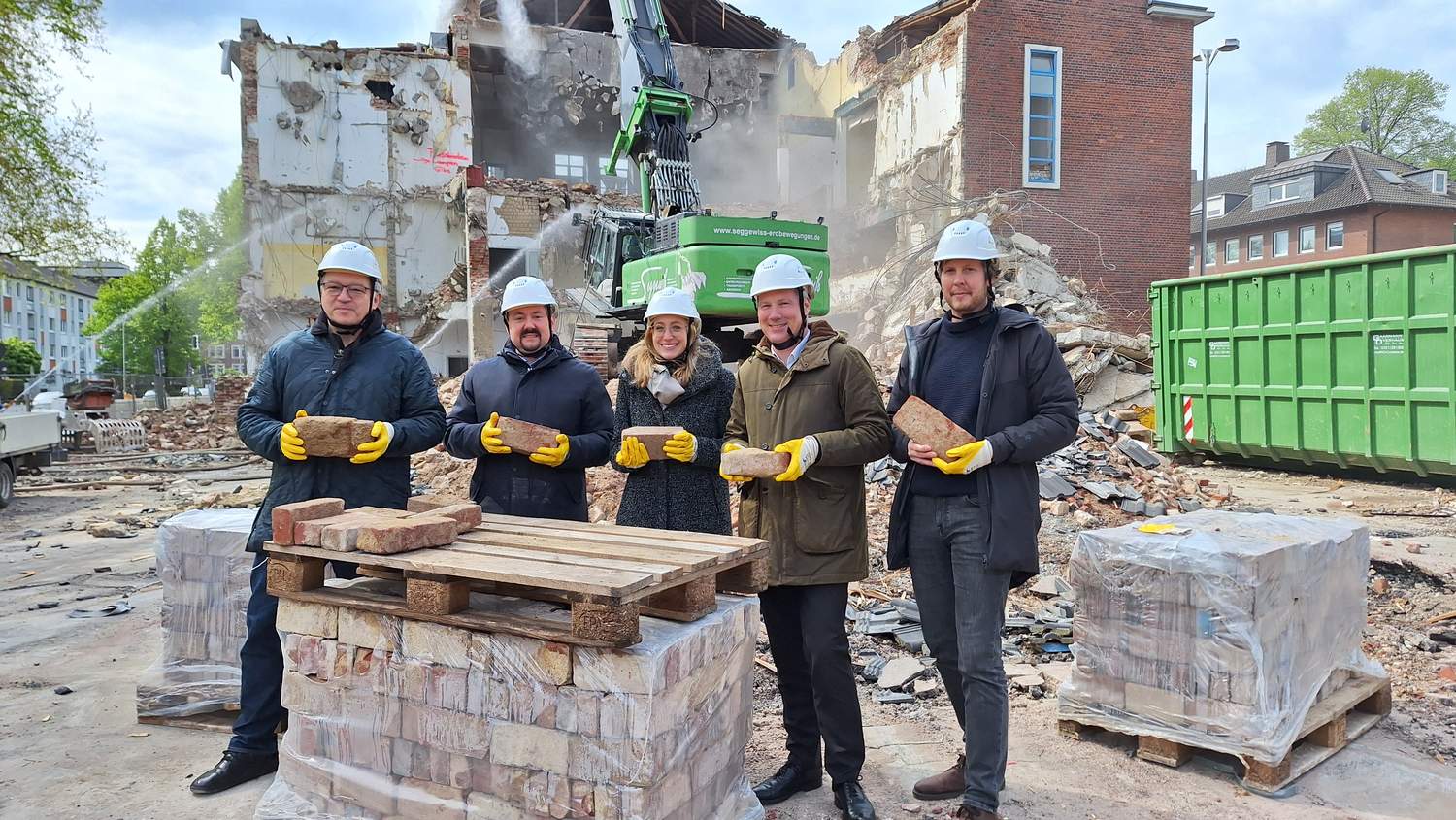 Die Projektverantwortlichen vor Ort mit den Ziegelsteine, die im Neubau wieder zum Einsatz kommen werden