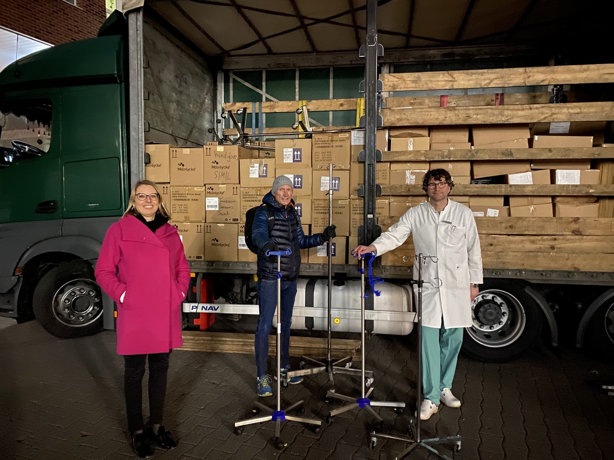 Drei Personen stehen vor einem beladenen LKW.